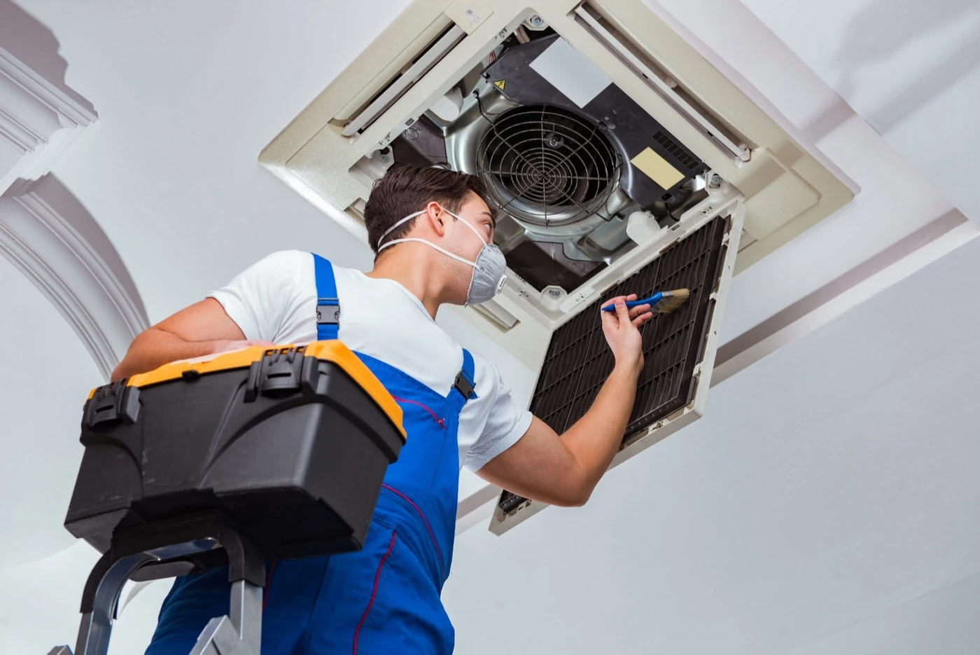Technician servicing a ceiling-mounted cassette air-conditioning system