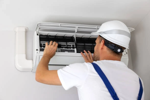 Technician inspecting filters in a wall-mounted air-conditioning unit